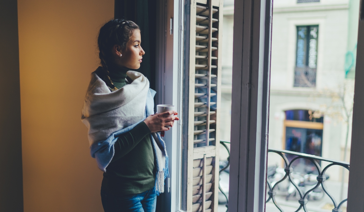 Woman looking out a window abroad, reflective and far from home
