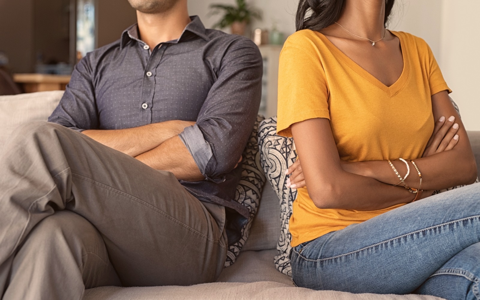 Intercultural couple sitting apart, disconnected on a couch